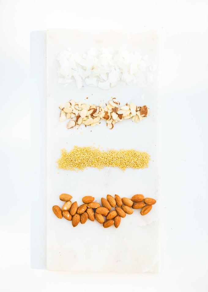 ingredients for homemade almond coconut kind bars on marble slab, almonds, coconut, puffed rice millet