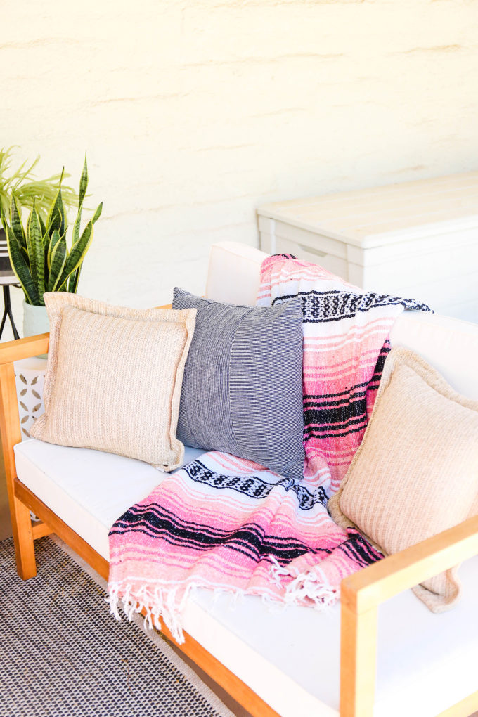 striped mexican serape blanket rests on modern white outdoor loveseat