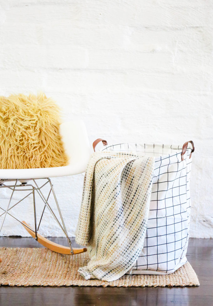 grid-patterned storage canvas bin with blanket hanging out 