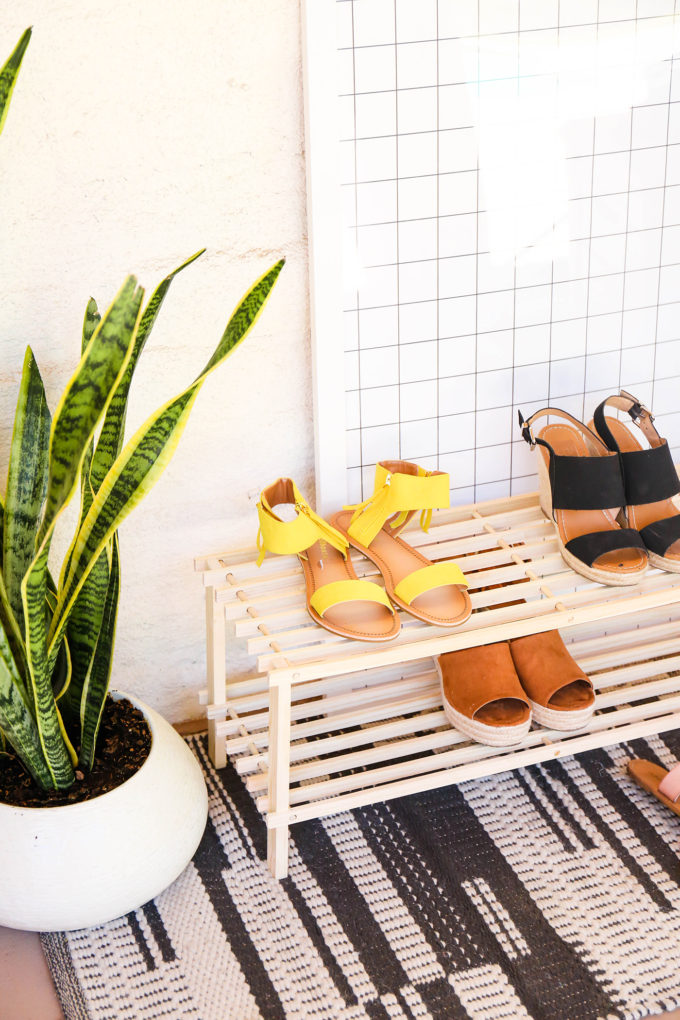 unfinished wood shoe rack with plants and shoes on it