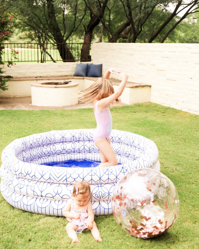 little girl twirling in swimsuit in inflatable pool 