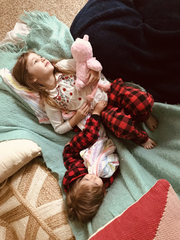 sisters cuddling in a pile of blankets 