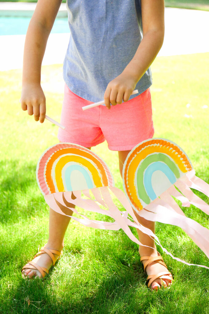 kid playing with paper plate rainbow puppets 