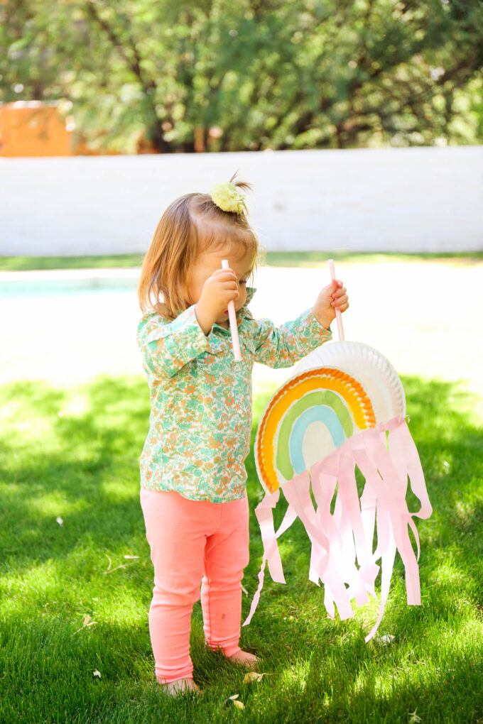 kid playing with paper plate rainbow puppets 