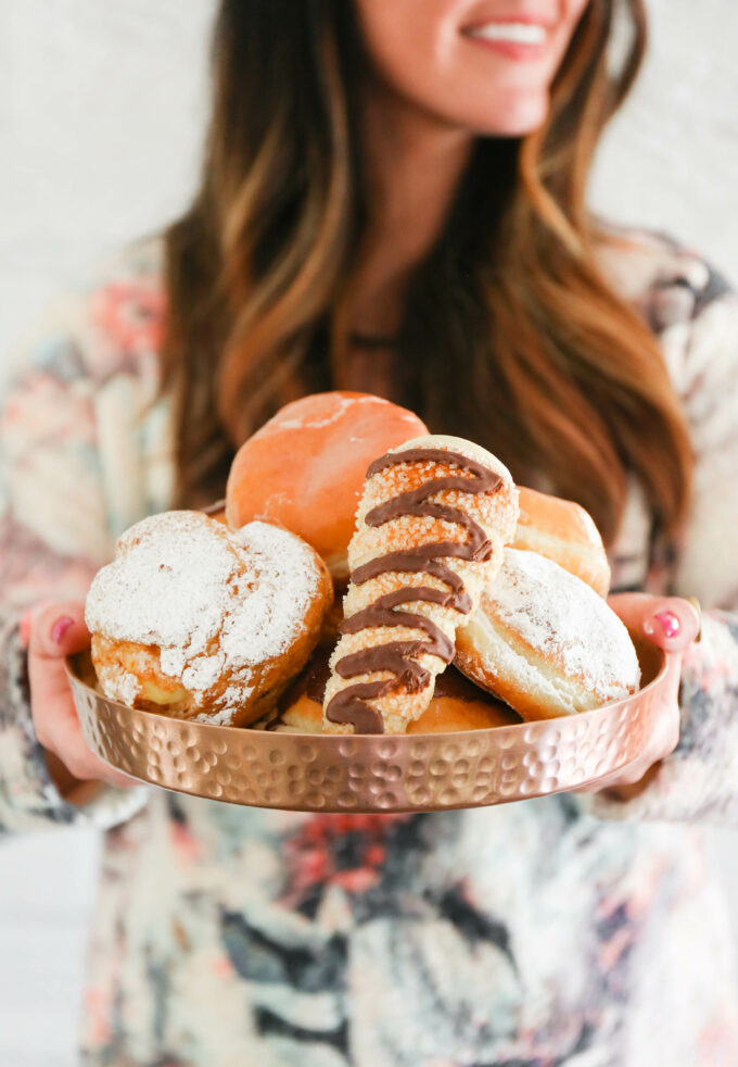 Hand holding plate of donuts 