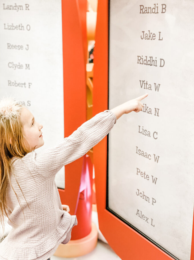 little girl pointing to her name on Santa's "nice" list