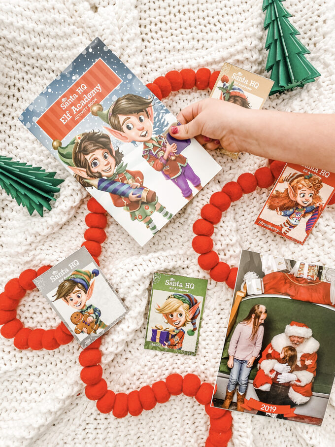 little girl reaching for elf academy activity book with other activities scattered with christmas items 