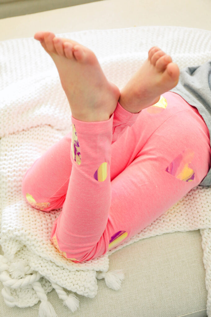 little girl crossing legs with pink valentine's day leggings
