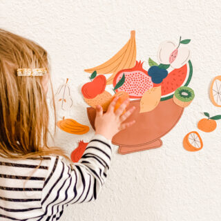 little girl placing fruit stickers on wall