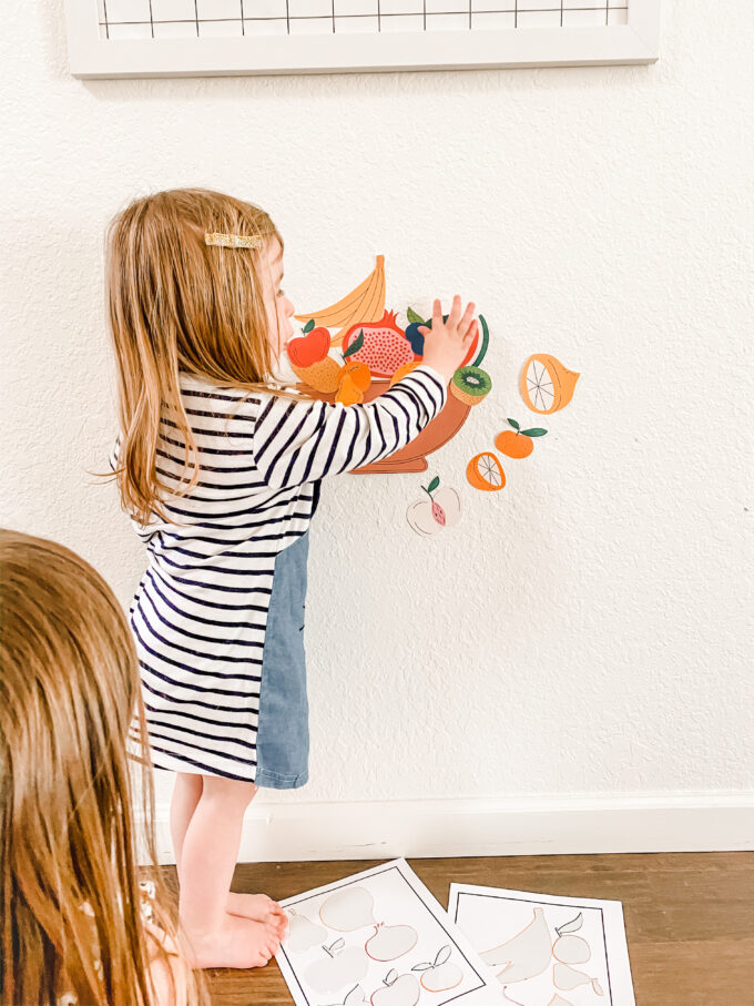 fruit stickers being placed on wall by little girl 