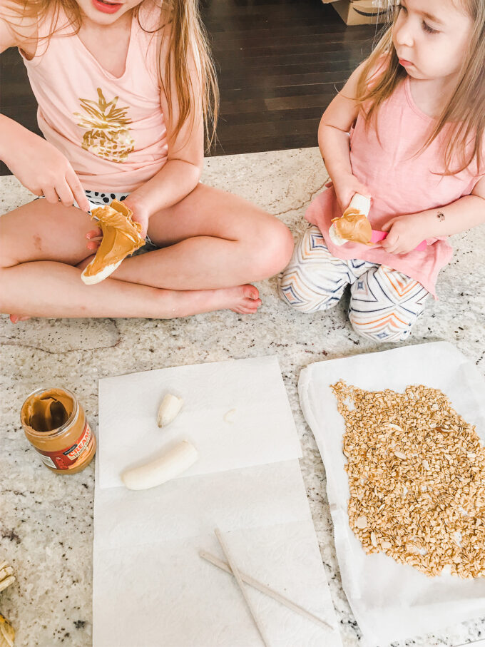 little girls spreading peanut butter on bananas 