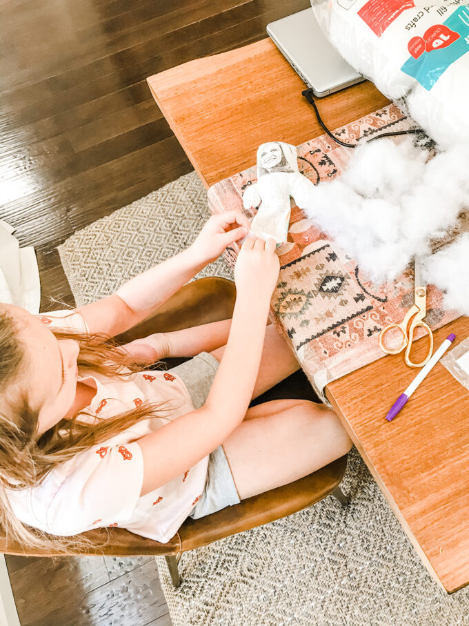 little girl stuffing homemade doll 