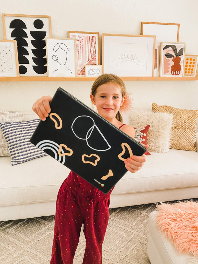 little girl holding chromebook with personalized stickers 